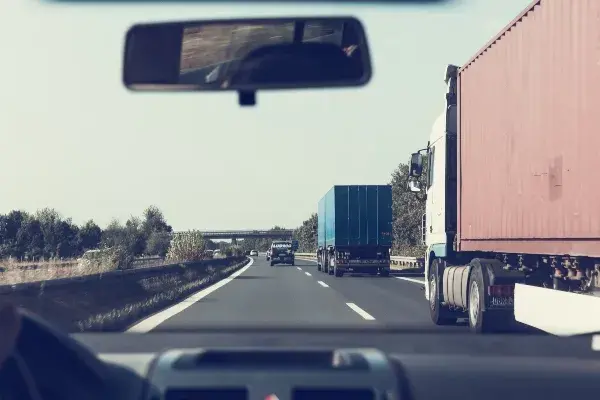 Camion rojo y azul visto desde dentro de un coche